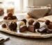Handmade chocolates arranged on a tray with glossy finishes, cocoa dust, nuts, and fresh fillings